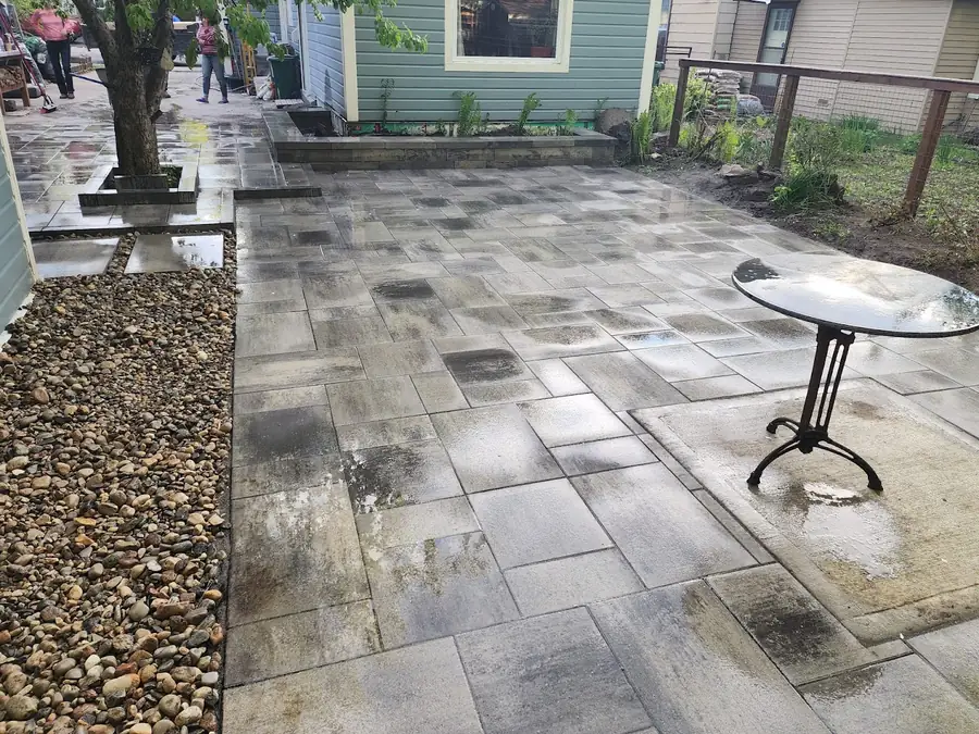 A courtyard patio of large grey interlock stones with a small table and a tree