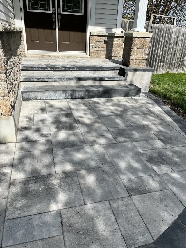 Grey stone steps and a wide landing leading up to a pair of dark doors